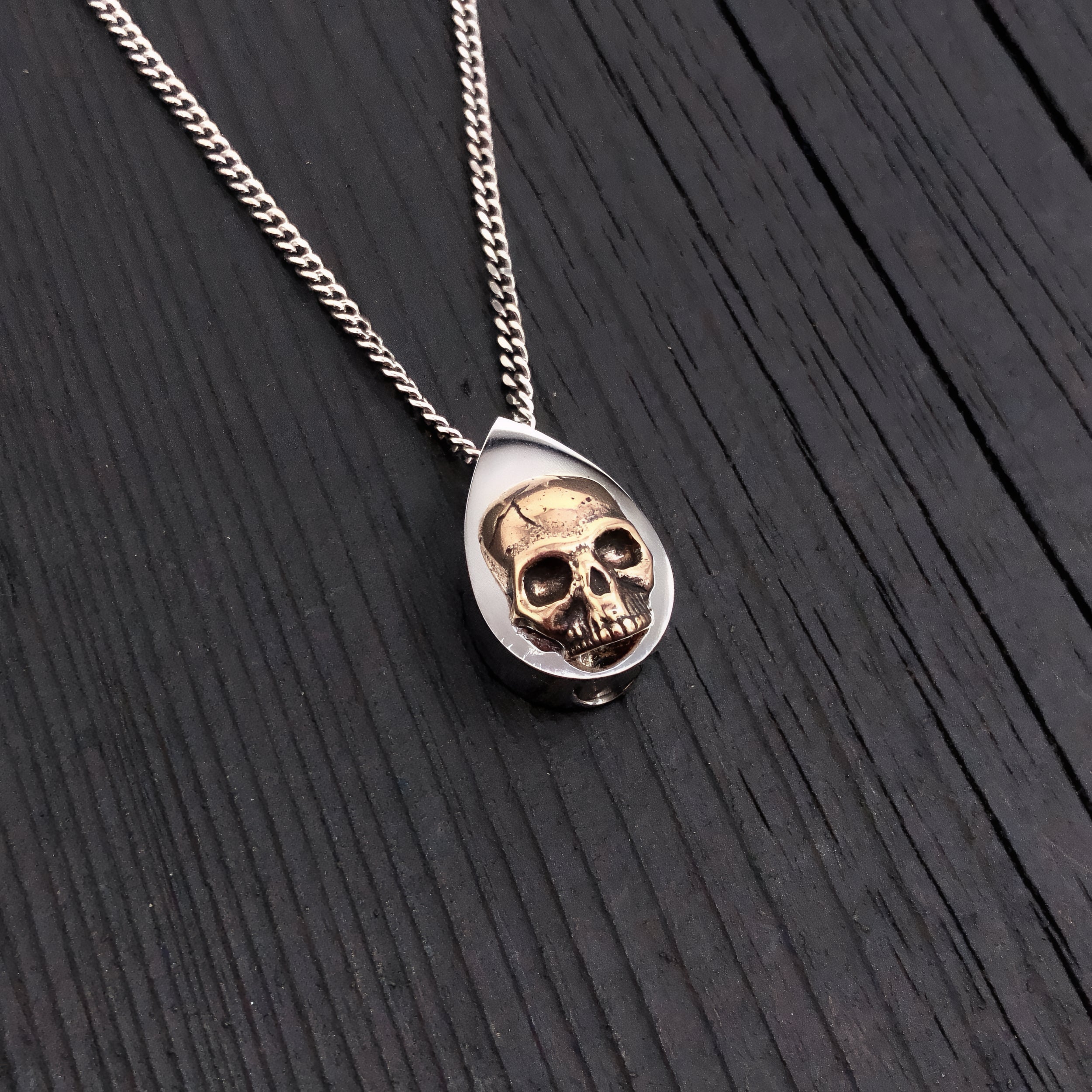 My cremation urn pendant is made of stainless steel with a mirror finish. Mounted on the front is a detailed bronze human skull. A discreetly placed screw can be removed from the bottom revealing a small chamber for a small amount of cremated ashes