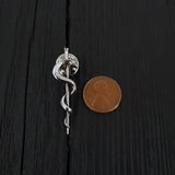 Silver snake pin beside penny, intricate design, contrast | Moon Raven