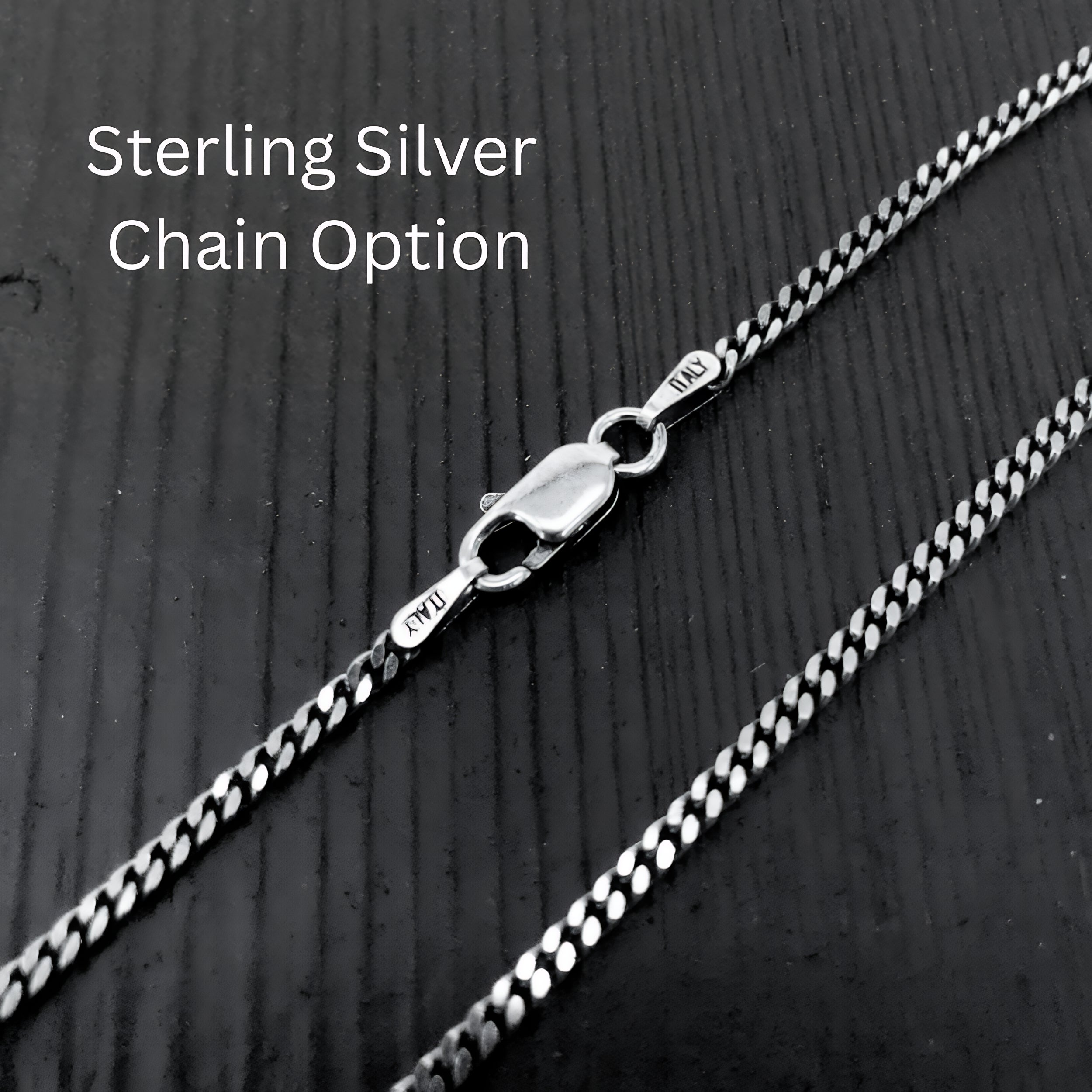 A close-up view of a silver chain necklace with a clasp, resting on a textured surface.